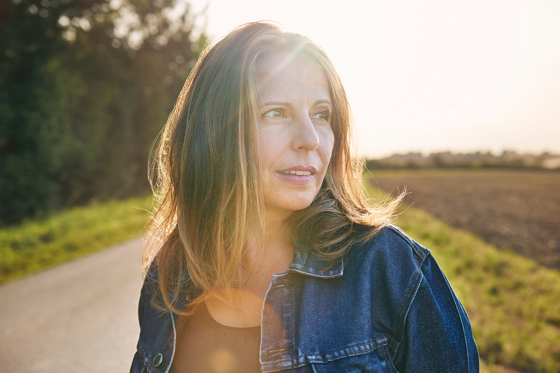 Portrait einer Frau im Gegenlicht auf einem Feldweg