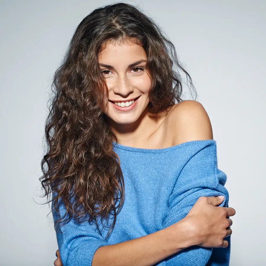 Junge Frau mit langen Locken im blauen Pullover, Studio