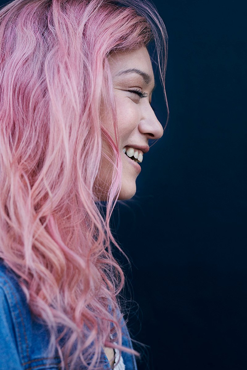 Profil einer Frau mit pinken Haaren vor dunklem Hintergrund