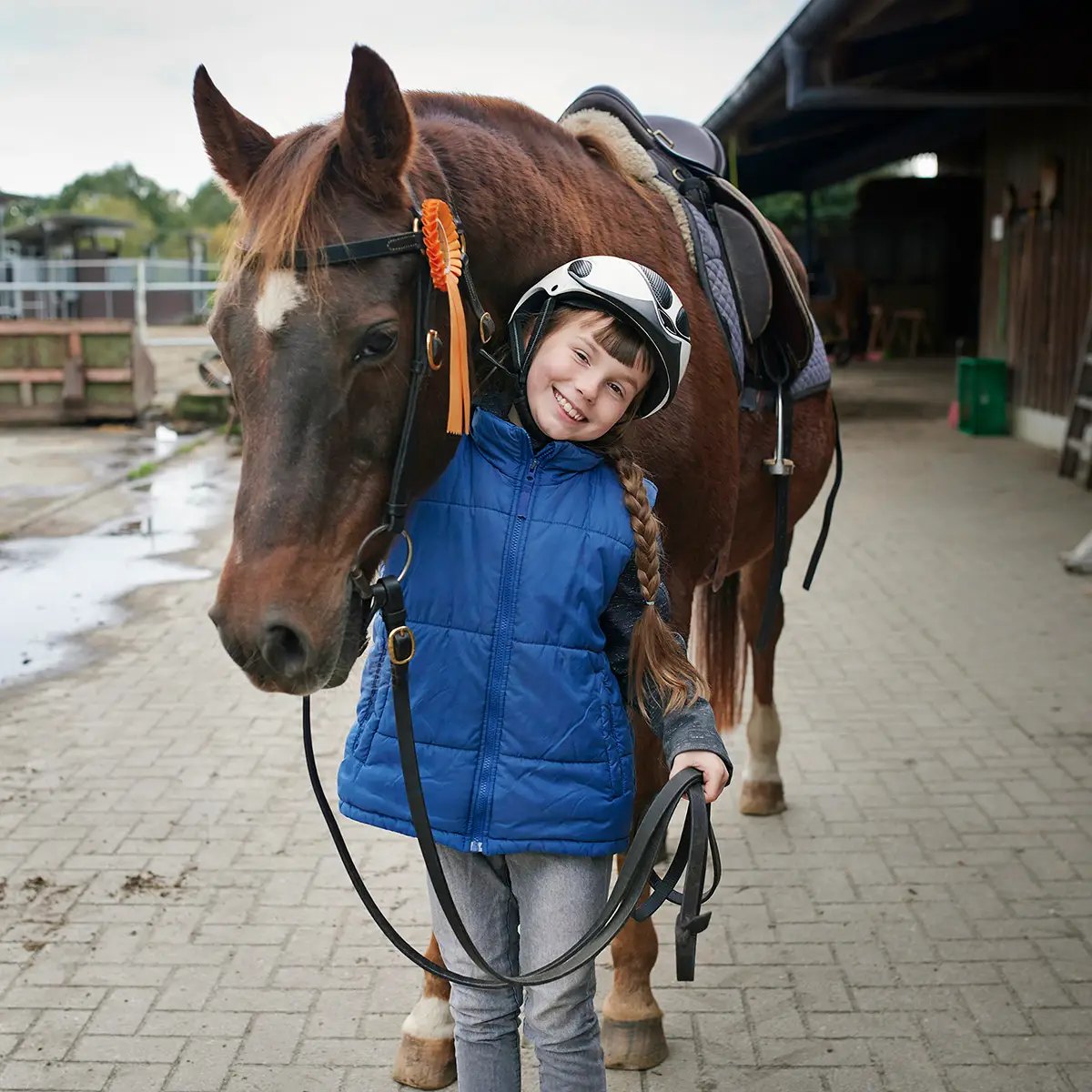 Mädchen führt ihr Pony über den Stallhof