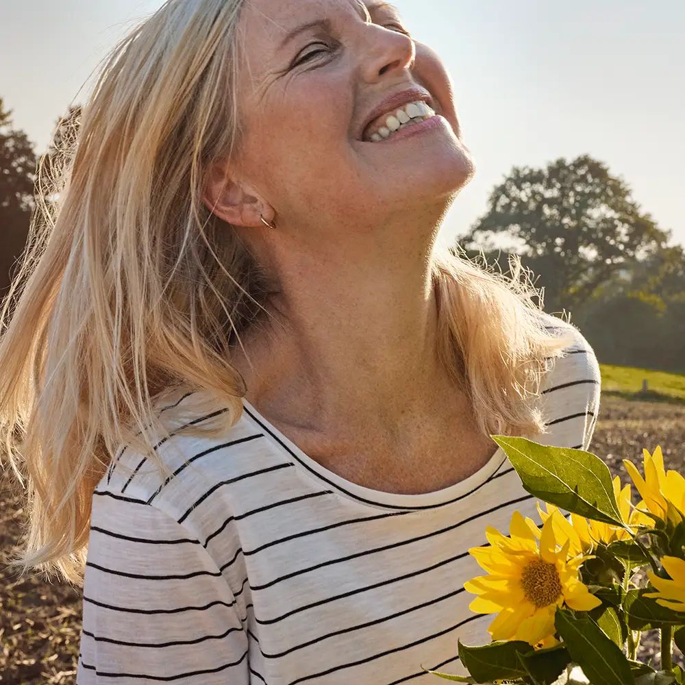 Lachende Frau mit Sonnenblume auf dem Feld
