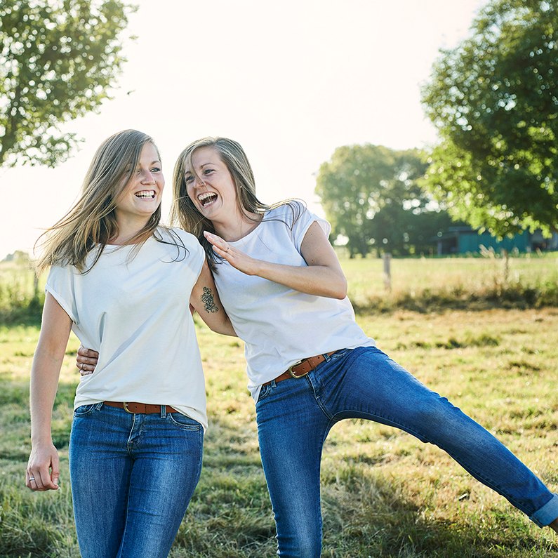 Zwei Freundinnen lachen auf einer Wiese