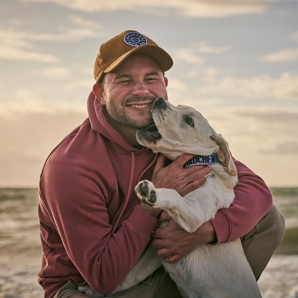 Mann mit seinem Labrador am Strand