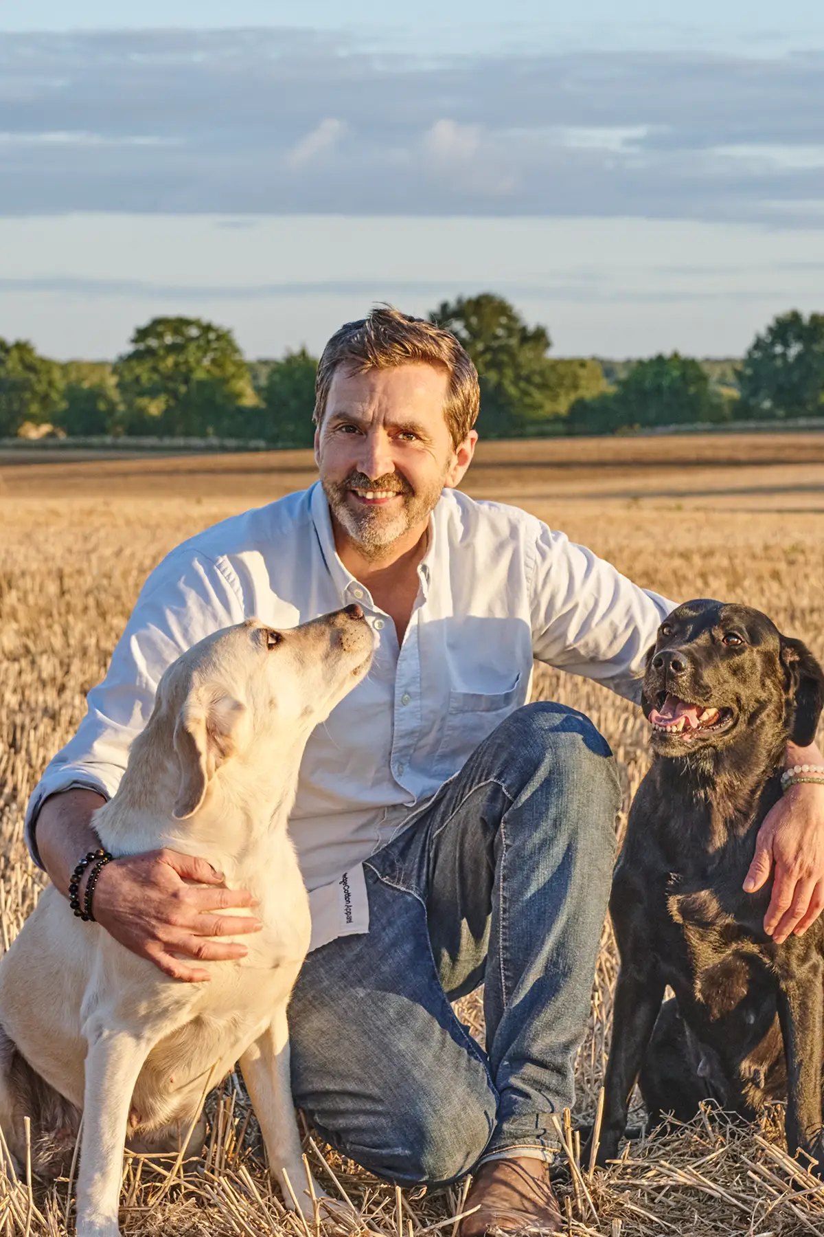 Uwe Krejci mit seinen beiden Labradoren auf einem Stoppelfeld im Abendlicht