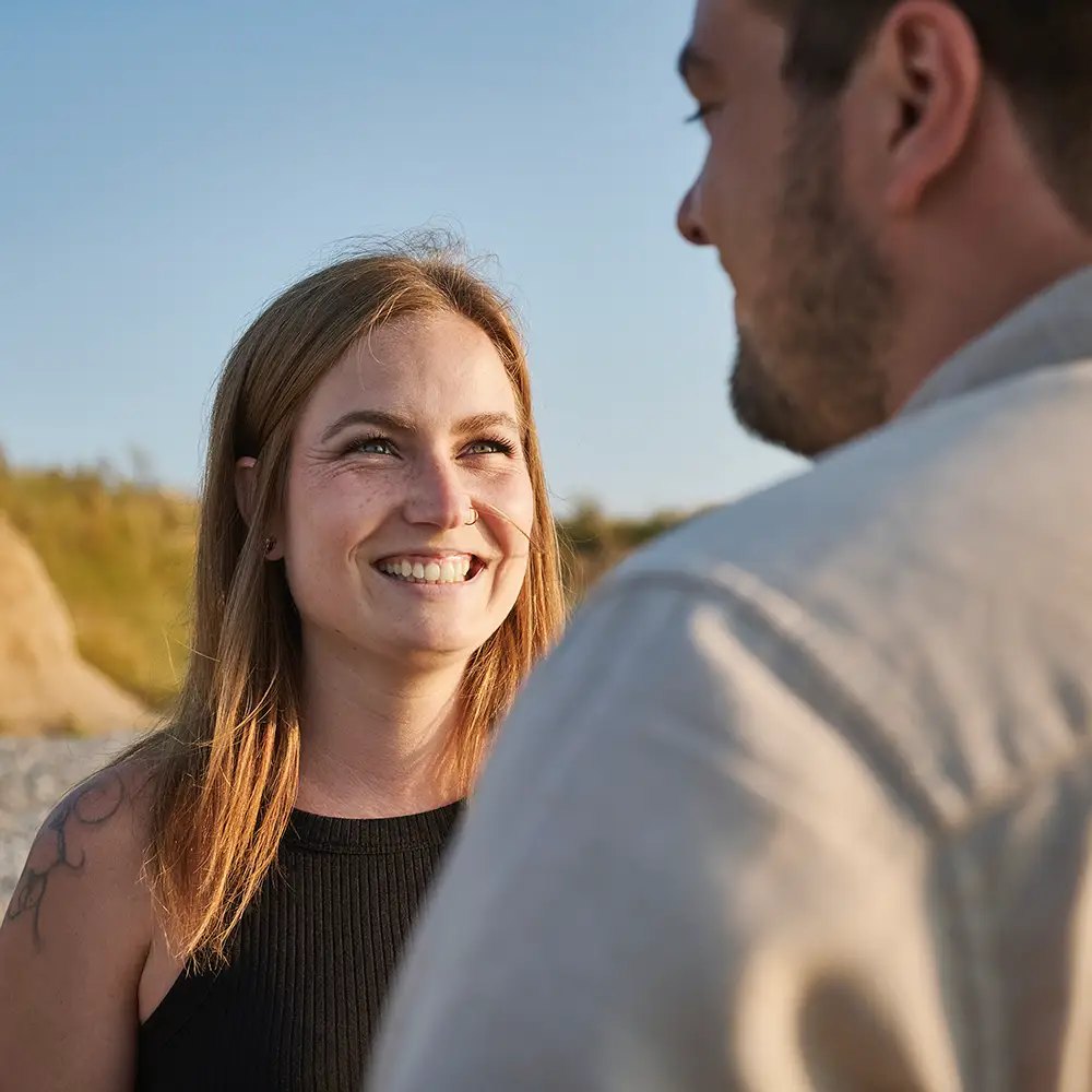 Lachende Frau am Kliff, ihr Partner im Vordergrund
