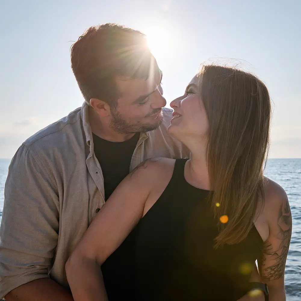 Paar küsst sich vor der untergehenden Sonne am Meer