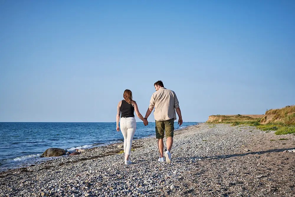 Paar geht Hand in Hand am Ostseestrand entlang