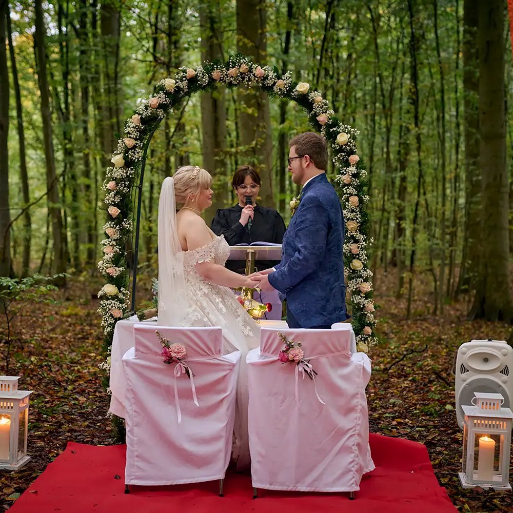 Freie Trauung im Wald unter einem Blumenbogen